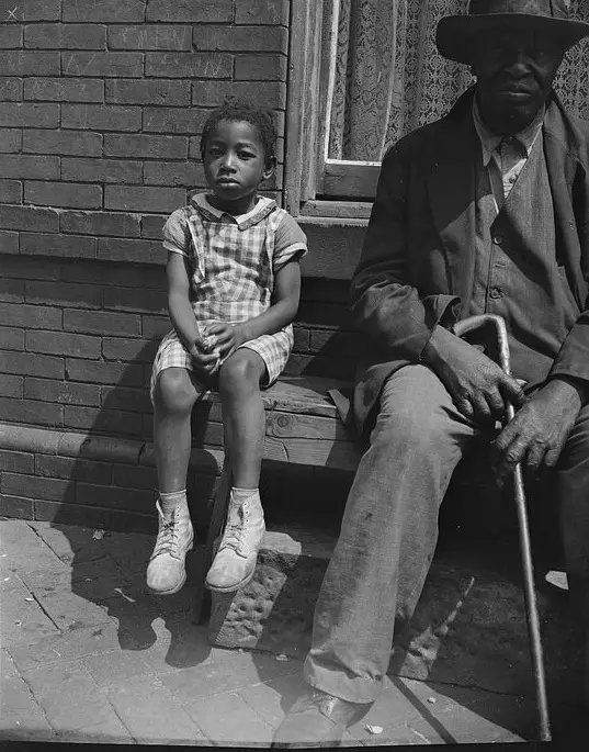 Black and white photo of a grandfather and young grandchild on front steps